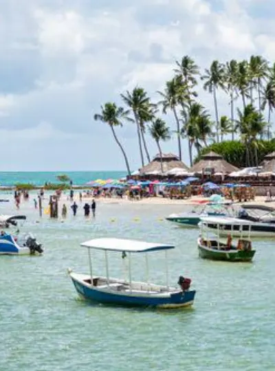 Praia com barcos e barracas de palha à beira d'água